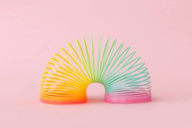 Pembe arka planda gökkuşağı plastik yaylı oyuncak