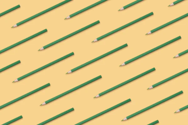 Pattern composition of green pencils on a yellow background. Top view. Flat lay. Back to school concept.