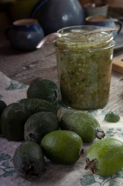 Fayjoa meyveleri ve eski mutfağın ahşap masasında bir kavanoz reçel.