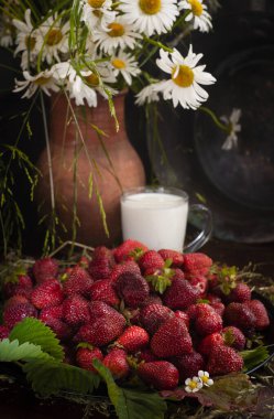 Bir fincan sütlü taze çilek ve koyu arkaplandaki ahşap masada yabani papatyalar, seçici odak, dikey, seçici odak, sade anahtar..