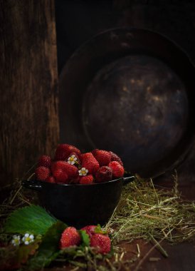 Siyah kase taze çilek ahşap masa üzerinde koyu arka planda kuru çimen, seçici odak, dikey, seçici odak, sade anahtar.
