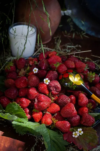 Bir fincan sütlü taze çilek ve ahşap bir kaşık üzerinde ahşap masa üzerinde koyu arka plan, dikey, seçici odak, sade anahtar.