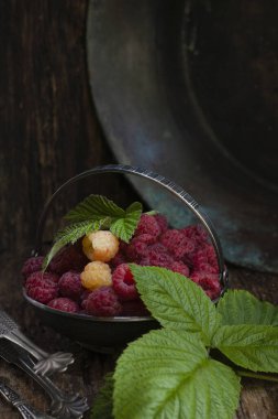 Ahududu, ahududu yaprağıyla gümüş kasede ahududu, ahududu, ahududu, ahşap masa, sade anahtar, seçici odak, dikey, kopyalama alanı