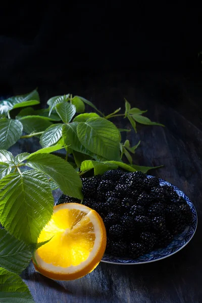 Blackberry em prato de metal com fatia de laranja e folhas verdes — Fotografia de Stock