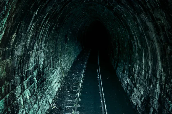 Dark flooded single track tunnel. Old abandoned railway tunnel.