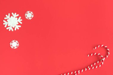 Şeker kamışları ve kırmızı arka planda dekoratif kar taneleri. Yukarıdan bak. Seçici odak