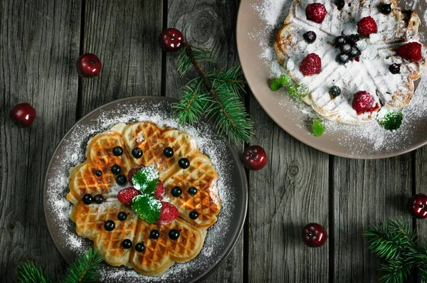 Homemade round waffles with berries and powdered sugar. Christmas composition. Natural light. Top view