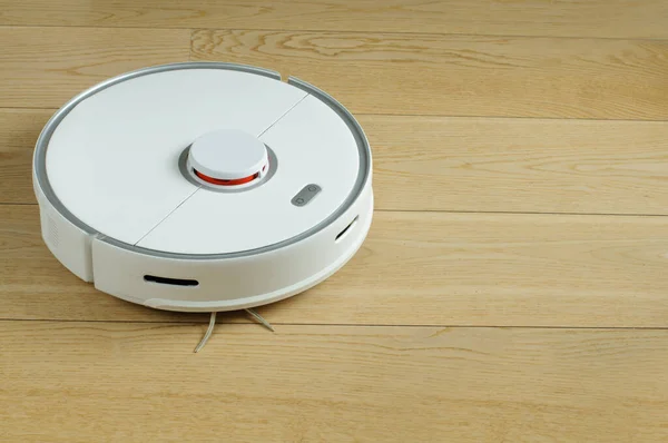 Robot elektrik süpürgesi, açık ahşap parkede bir odayı temizlerken...