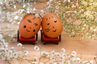 İki Paskalya yumurtası, oyuncak mobilya, çiçekler. Bulanık arkaplan ve arkaplan, seçici odak.