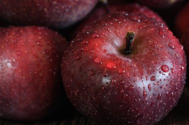 Olgun kırmızı elmaları su damlacıklarıyla yakından çek. Karanlık arka plan. Seçici odak