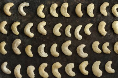 Koyu bir arka planda kaju fıstığı dizilmiş. Düz yatış, üst görünüm, seçici odak