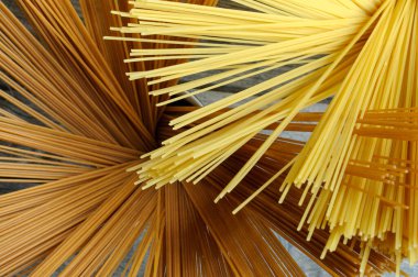 Tahta bir masada, iki tip makarnanın içinde çiğ spagetti. Seçici odak