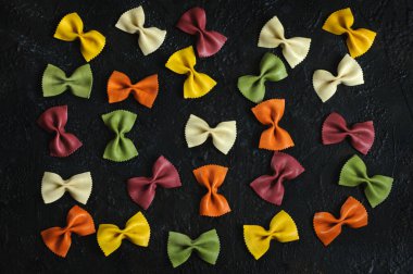 Makarna yayları, siyah arka planda farklı renkler. Yukarıdan bak. Düz yatıyordu