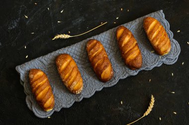 Kırsal, beyaz ekmek somunları gri bir bez üzerinde. Siyah arkaplan. Üst görünüm