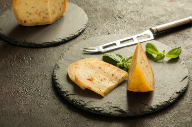 Tahtalarında otlar ve baharatlar olan peynir parçaları. Ev yapımı sert peynir. Doğal ışık, ön plana seçici odaklanma