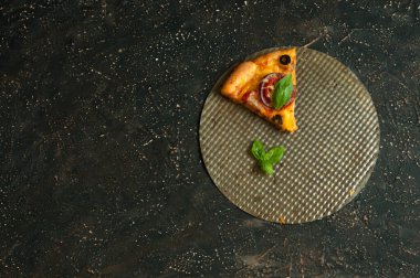 Fotokopi alanı olan koyu beton arka planda bir dilim lezzetli pizza. Düz yatış, üst görünüm, seçici odak