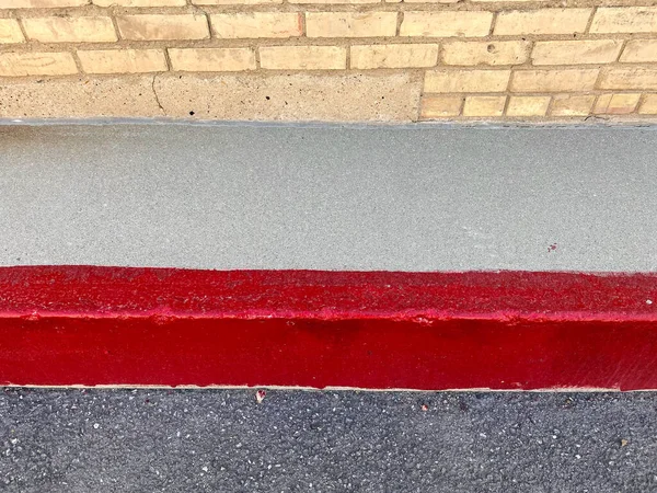 レンガ倉庫の建物の舗装と端を示す歩道に描かれた明るい赤いストリップ — ストック写真