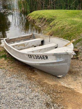 Bataklık gölü ya da nehir kıyısına çakılmış eski, çürüyen metal kürek teknesi.