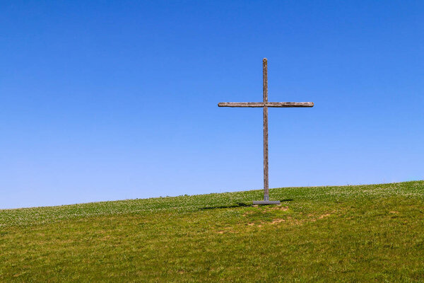 large wooden christian symbol cross standing on a grass hill or rural grassy hillside as a nature landscape religious background