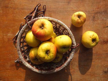 Wicer sepet içinde sarı elmalar.