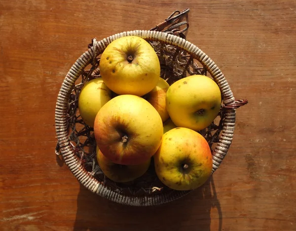 Wicer sepet içinde sarı elmalar.