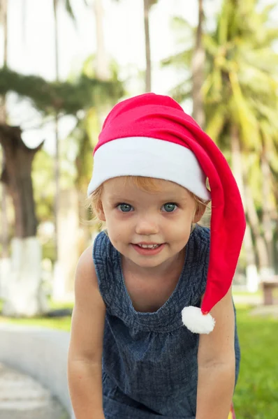 Cute girl in Santa hat having fun at the tropicals — Stock Photo, Image