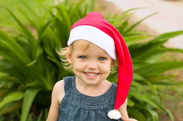 Cute girl in Santa hat having fun at the tropicals — Stock Photo, Image