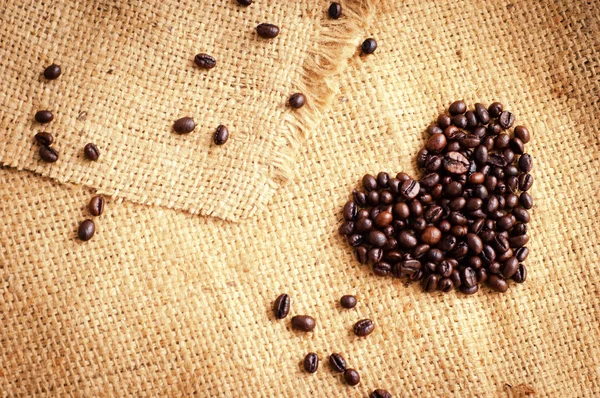 Heart with roasted coffee beans on the burlap background — Stock Photo, Image