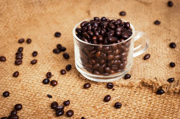 Tasse mit gerösteten Kaffeebohnen auf dem Hintergrund — Stockfoto