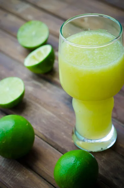 Limas verdes com suco de limão no copo — Fotografia de Stock