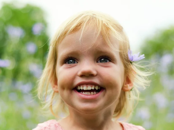 Roztomilá holčička v růžových šatech s úsměvem v parku — Stock fotografie