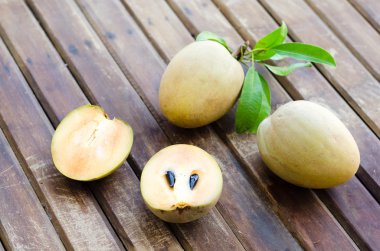 Yapraklarda ahşap arka plan ile meyve taze tatlı sapodilla