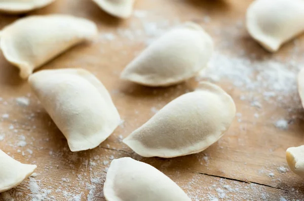 Flat dumplings sprinkled with flour on wooden surface — Stock Photo, Image