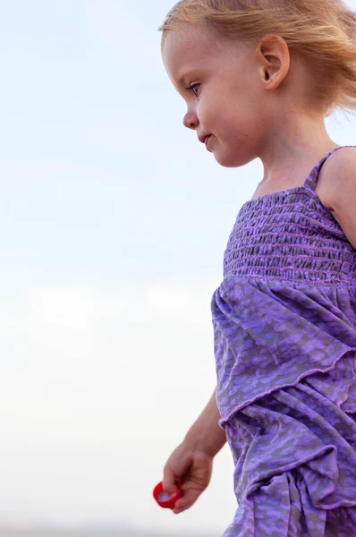Roztomilá holčička v purpurových šatech na mořském písku — Stock fotografie