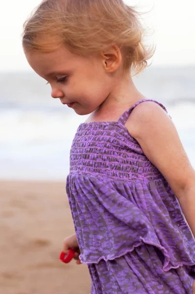 Cute little girl in purple dress playing on the sea sand — Stock Photo, Image