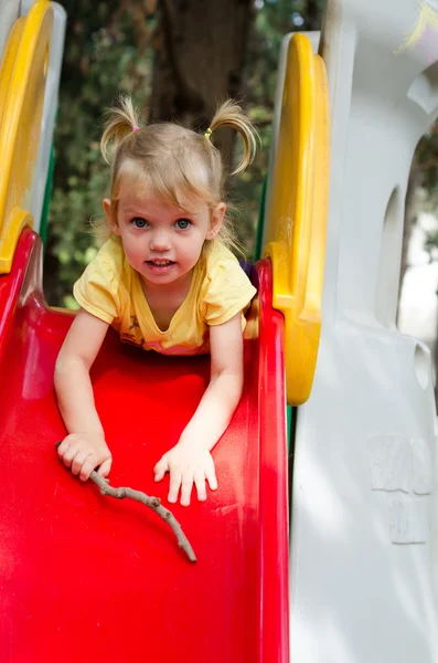 Little girl sliding from the plastic chute — Stock Photo, Image