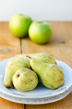 Elmalı arka plan üzerinde beyaz tabakta lezzetli yeşil armut