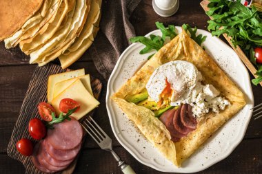 Rustik Kahvaltı: krep Galette'ye et, avokado, beyaz peynir ve haşlanmış yumurta beyaz plaka üzerinde