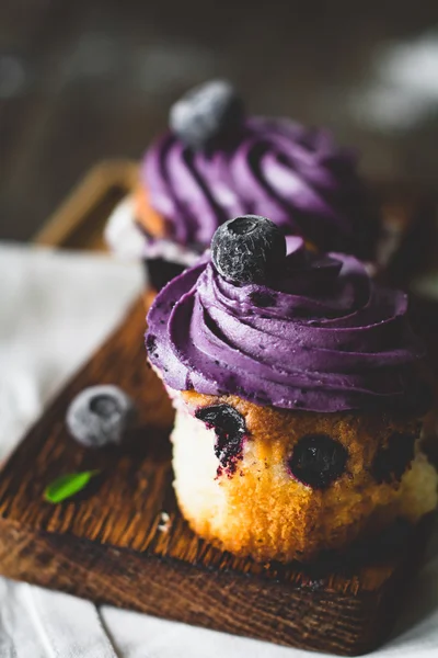 Blaubeer-Cupcakes mit lila Buttercreme auf Holzbrett, aus nächster Nähe. Selektiver Fokus, getöntes Bild — Stockfoto