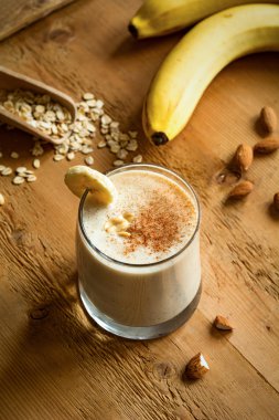 Taze muz smoothie yulaf ezmesi, tarçın ve fıstık ezmesi ahşap arka plan üzerinde