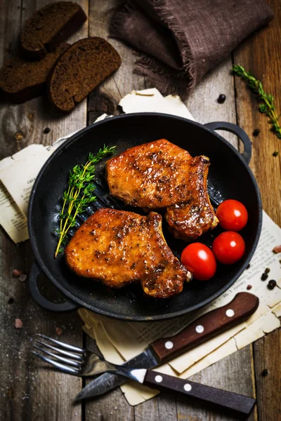 Chuletas de cerdo a la parrilla con tomillo y tomates cherry en sartén de hierro — Foto de Stock