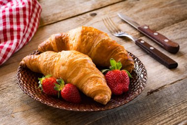 Taze kruvasanlar bir plaka üzerinde çilek ile