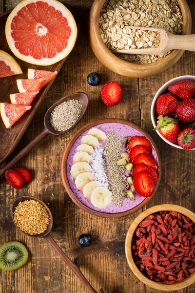 Ciotola di frullato sano con vari frutti e super alimenti su sfondo di legno — Foto Stock