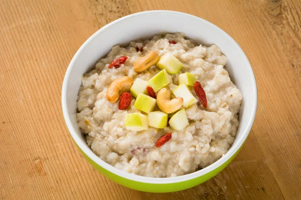 Oatmeal porridge with apple, goji berries and nuts, close up — Stock Photo, Image