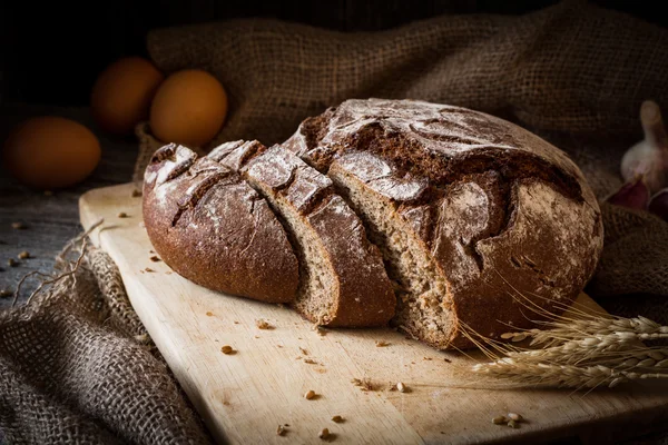 Loaf of bread sliced on wooden cutting board — Stock Photo, Image