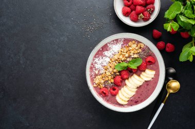 Siyah arka planda süper yiyecek malzemeleriyle ahududu kokteyli kasesi, üst manzara, fotokopi alanı. Vegan vejetaryen detoks smoothie kasesi