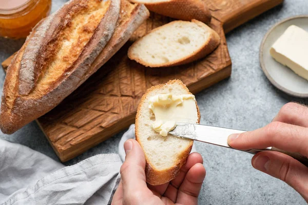 Smear butter on baguette bread. Making bread and butter sandwich