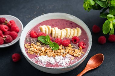 Ahududu, muz, granola ve hindistan cevizli pembe smoothie kasesi.