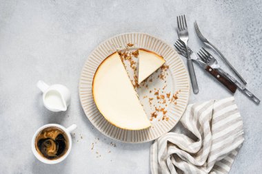Tabakta dilimlenmiş cheesecake ve gri beton arka planda kahve, üst manzara. Lezzetli peynirli pasta