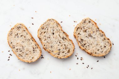 Mermer zemin üzerinde çoklu tahıllı ekmek dilimleri, üst manzara. Tohumlu sağlıklı ekmek.